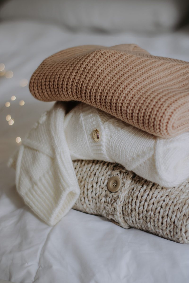 Stack of soft folded sweaters on a bed, illustrating heavyweight lounge fabric