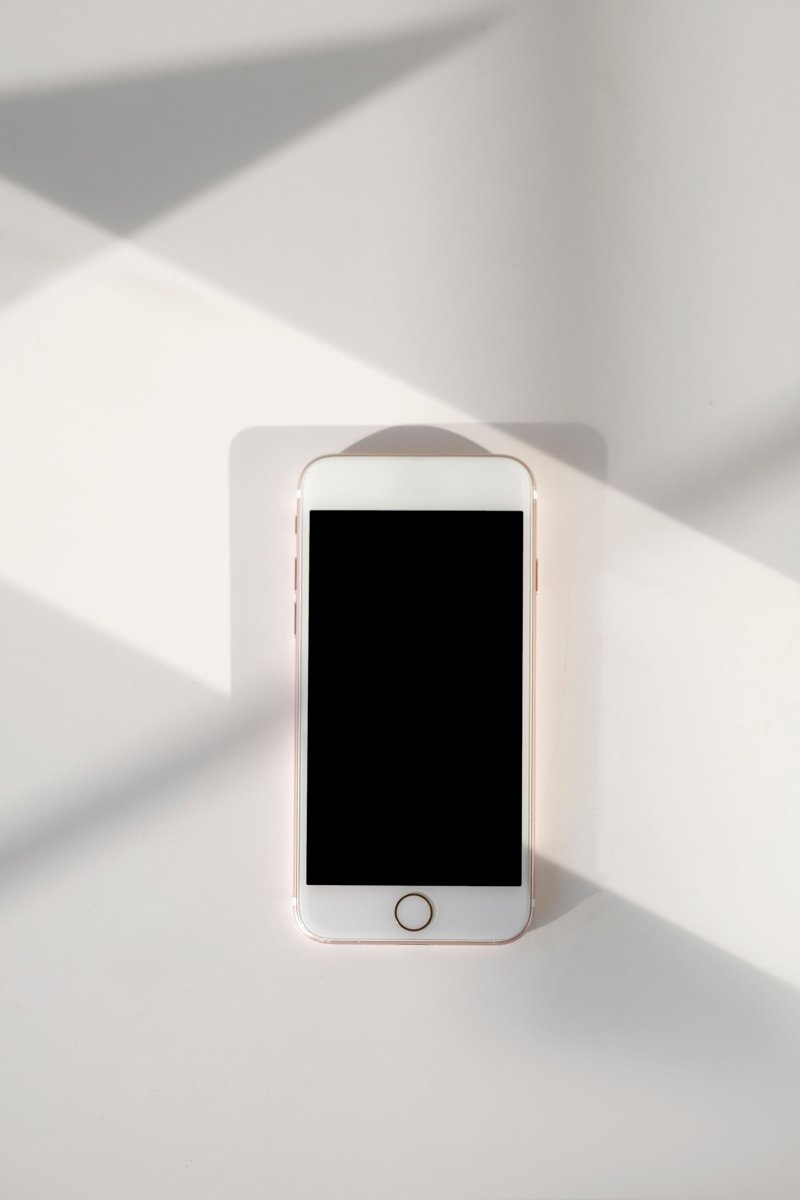 Smartphone with a dark screen lying on a white table in diagonal sunlight